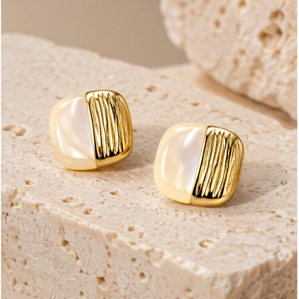Mother of pearl square stud earrings in gold styled on neutral stone