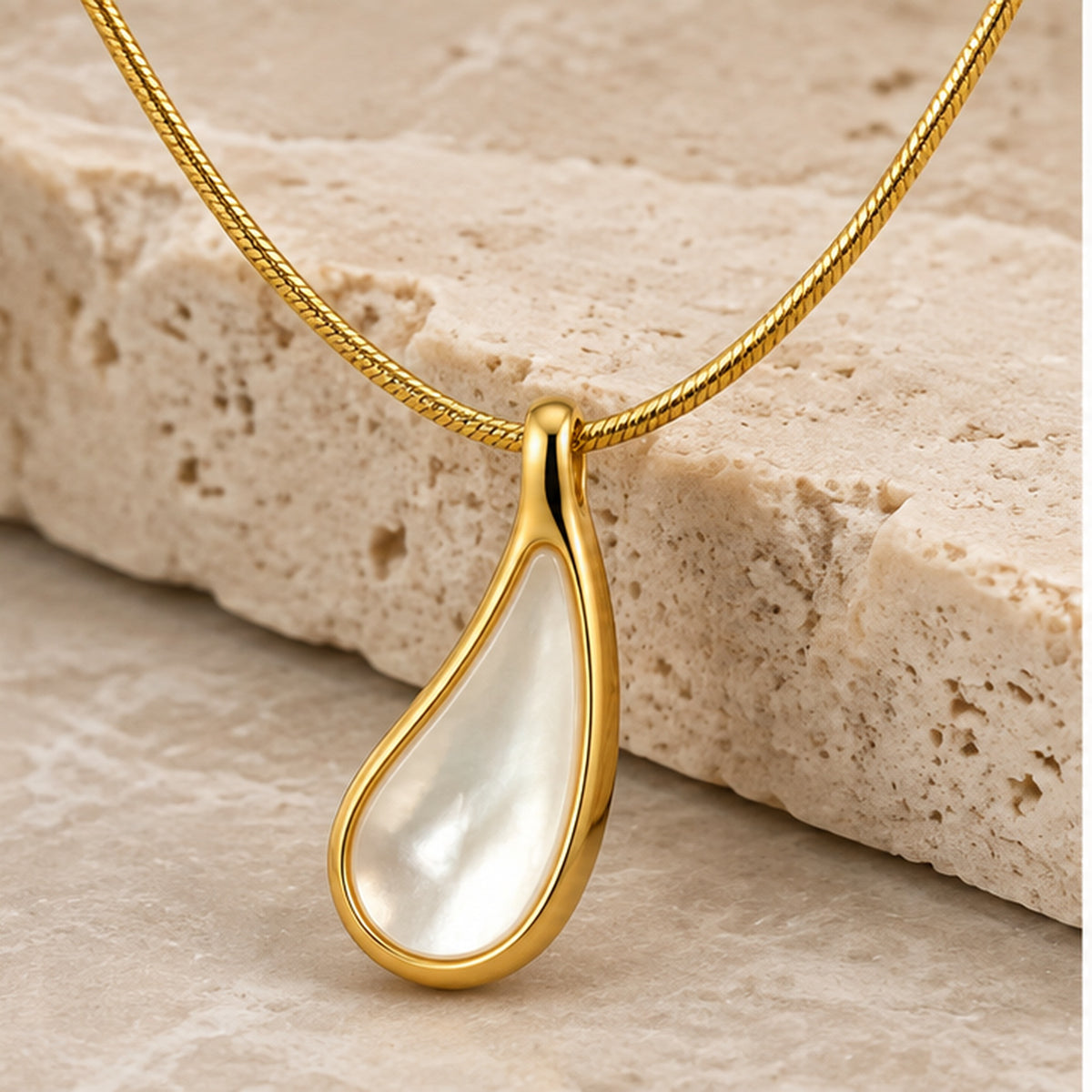 Mother of pearl teardrop pendant necklace in gold styled on neutral stone