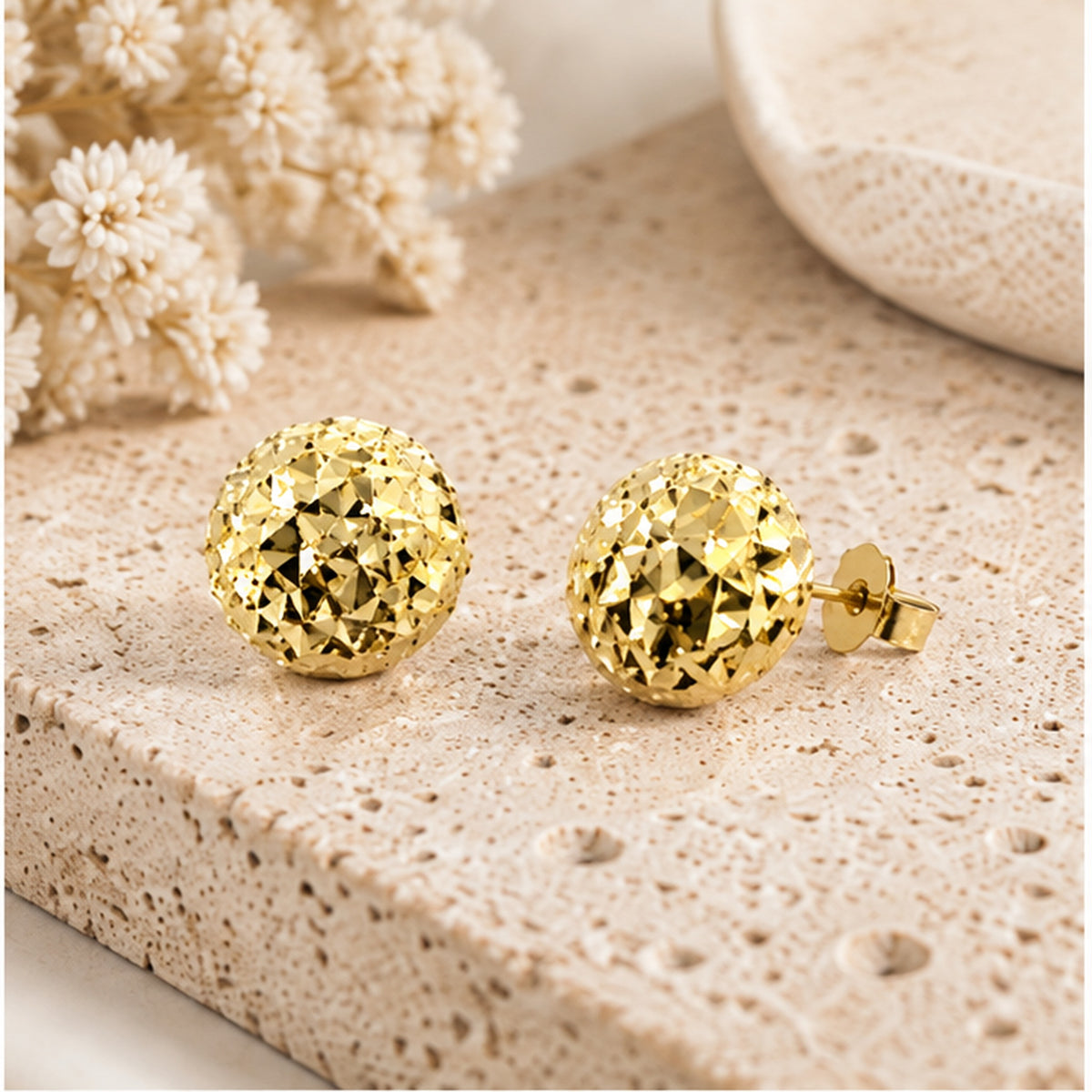 Faceted gold-tone dome stud earrings with solid sterling silver posts in a neutral studio setting