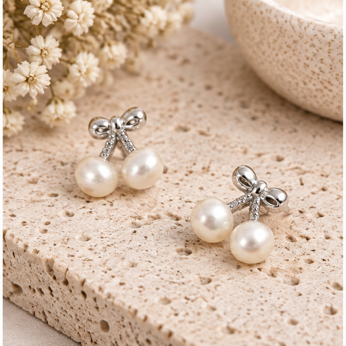 Real pearl bow double drop stud earrings in a neutral jewellery studio setting