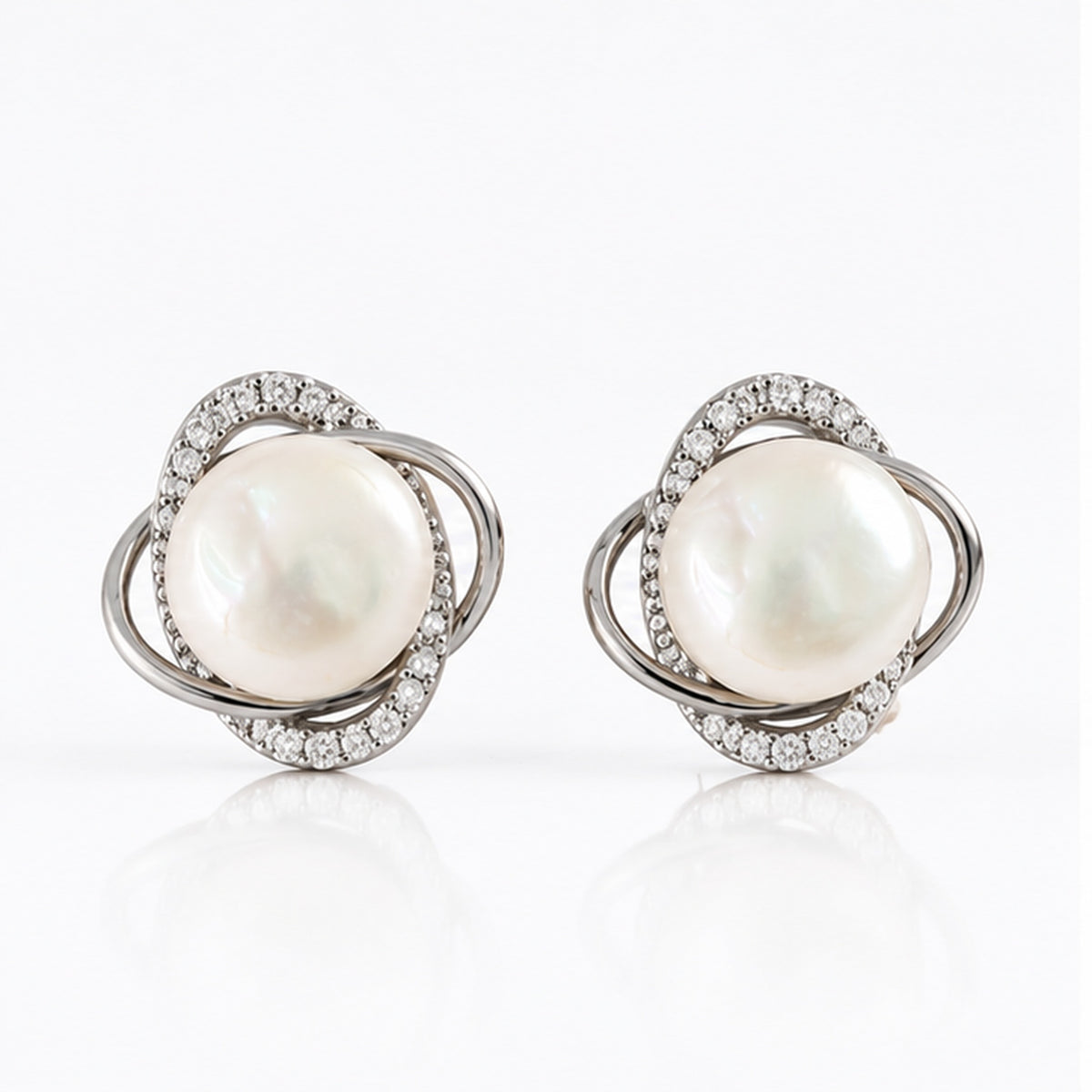 Real pearl orbit stud earrings with intertwined silver loops and clear stone accents on a clean white background